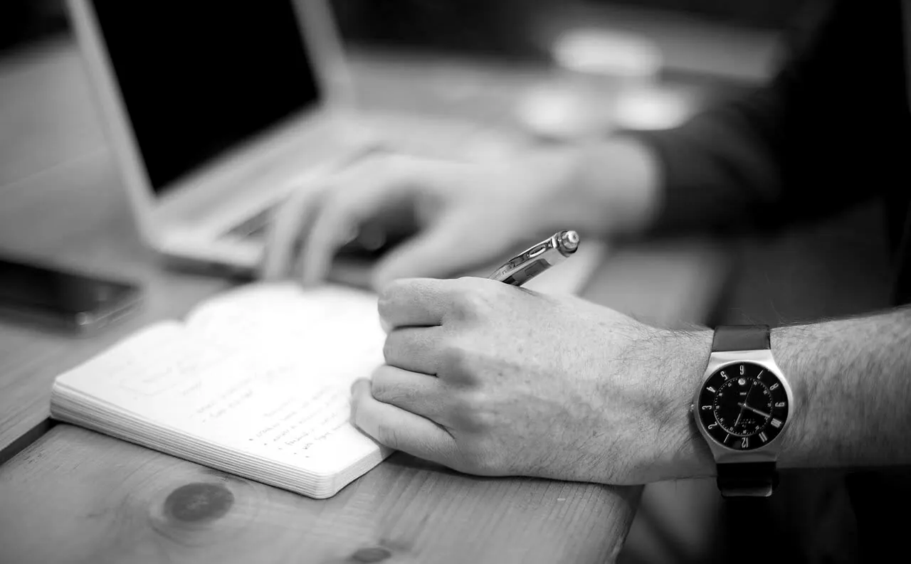 Hands writing in a notebook at a desk